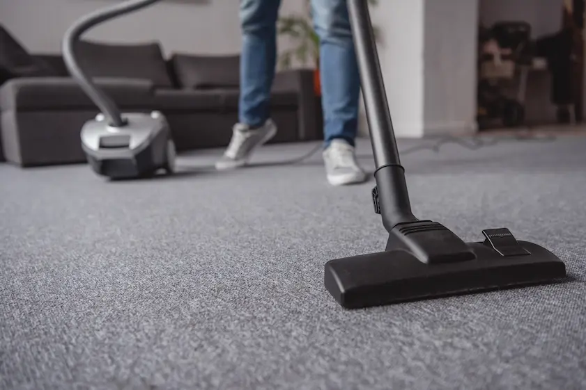 person hoovering carpet in an office